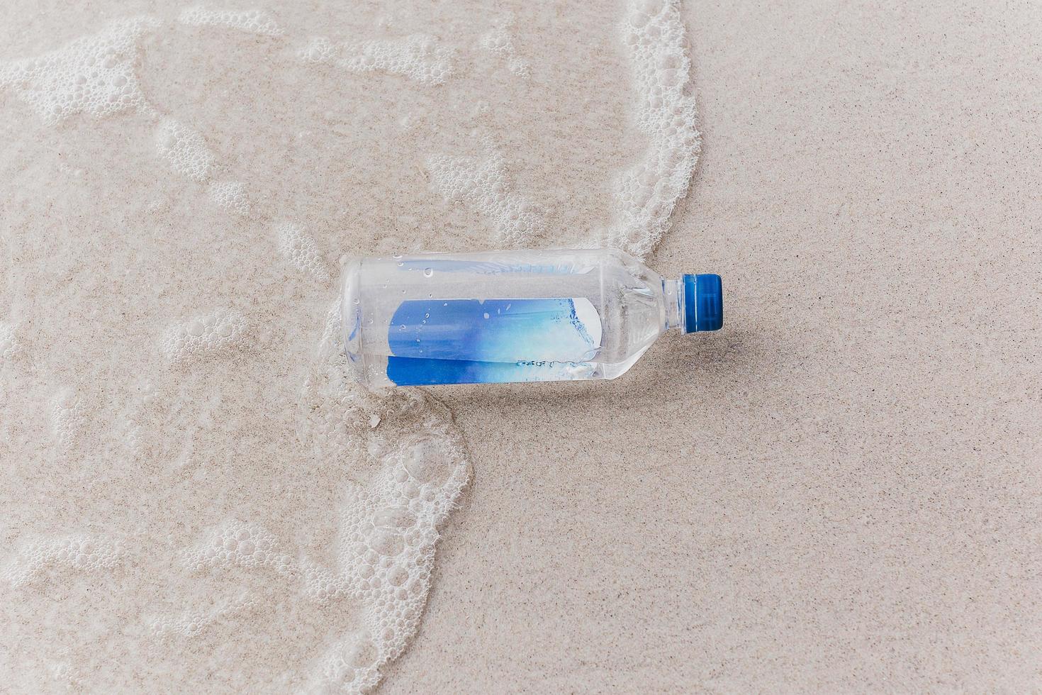 Bottle of drinking water on beach near the sea. photo