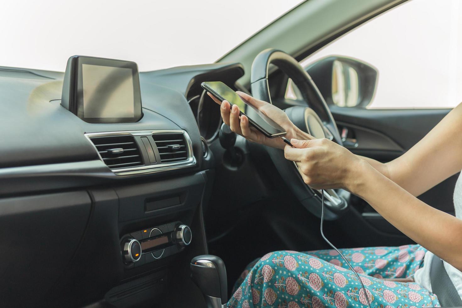 mujer conductora cargando su teléfono inteligente en el auto. foto