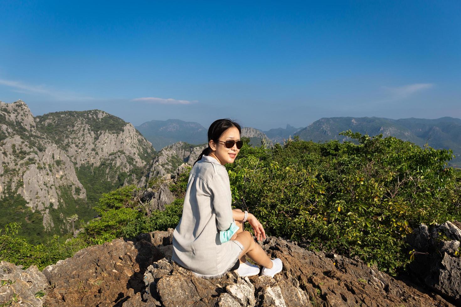 Asian woman with sunglasses sit on the top of the mountain. photo