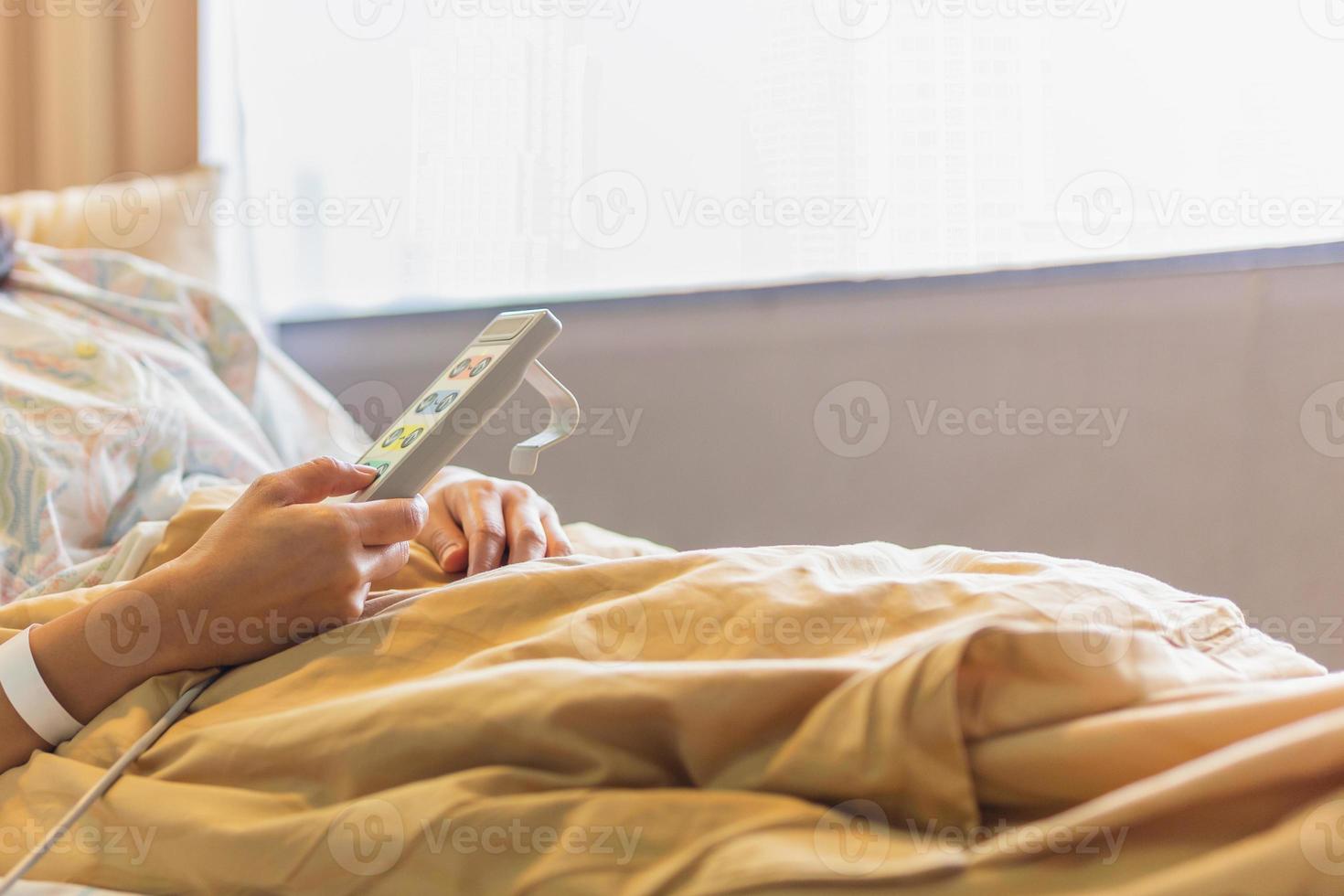 Woman patient hand using remote control for adjust level bed in hospital. photo