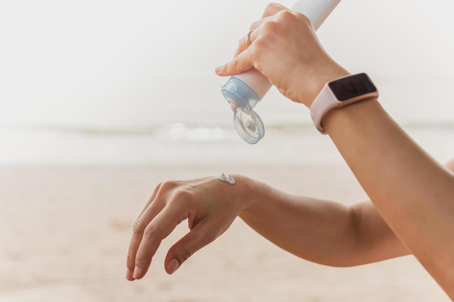 Woman squeezes sunscreen out of a tube on the sea beach UV protection. photo