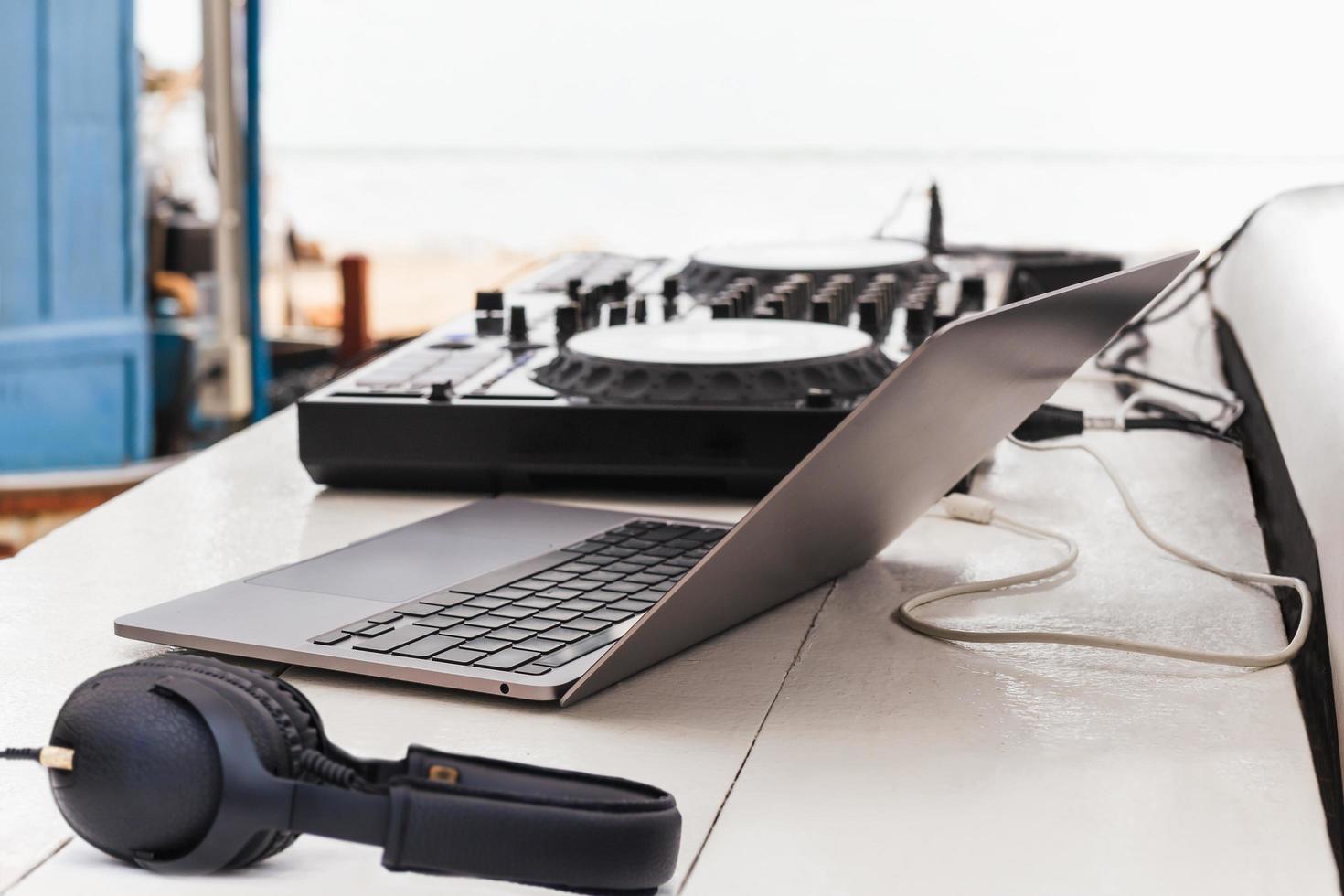 DJ sound control table mixing with headphone and laptop computer on table outdoors. photo