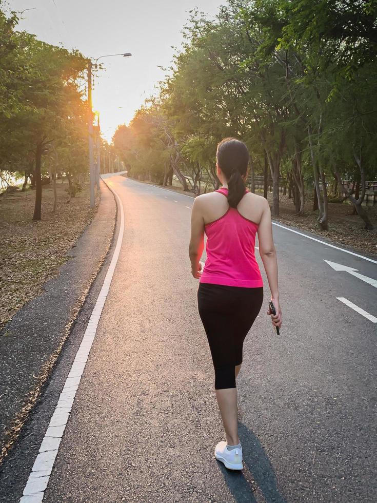Full length woman exercise walking in the park with sunset. photo