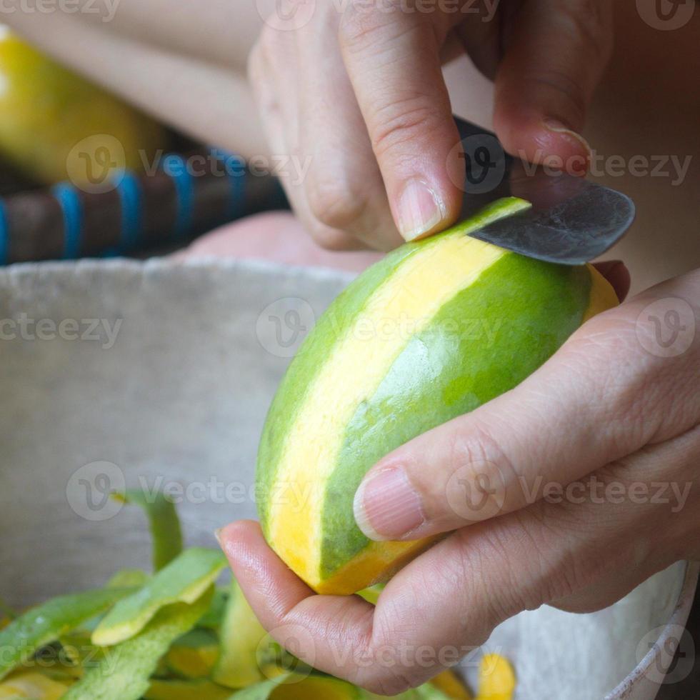 Woman hand using a knife to peel ripe mango. The local fruits are sweet