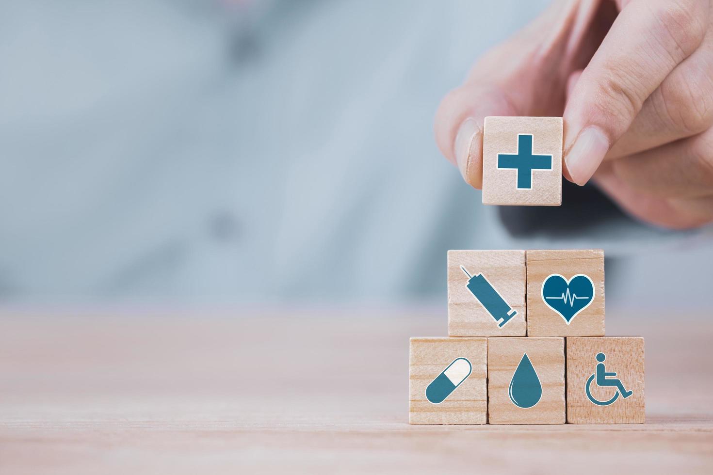 Businessman chooses a emoticon icons healthcare medical symbol on wooden block , Healthcare and medical Insurance concept photo