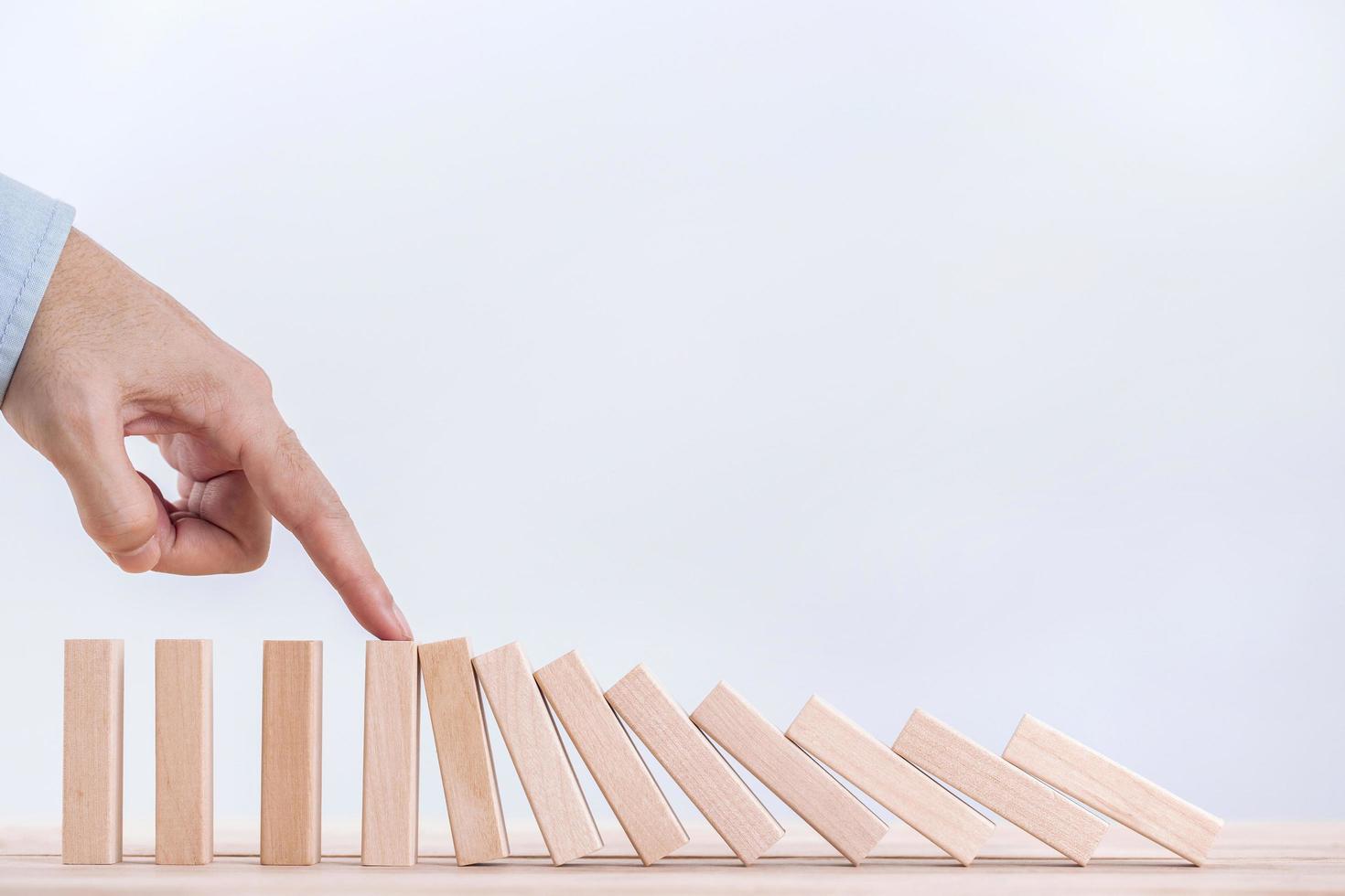 la mano del hombre de negocios detiene el efecto dominó para la gestión y la solución, la estrategia conceptual y la intervención exitosa foto