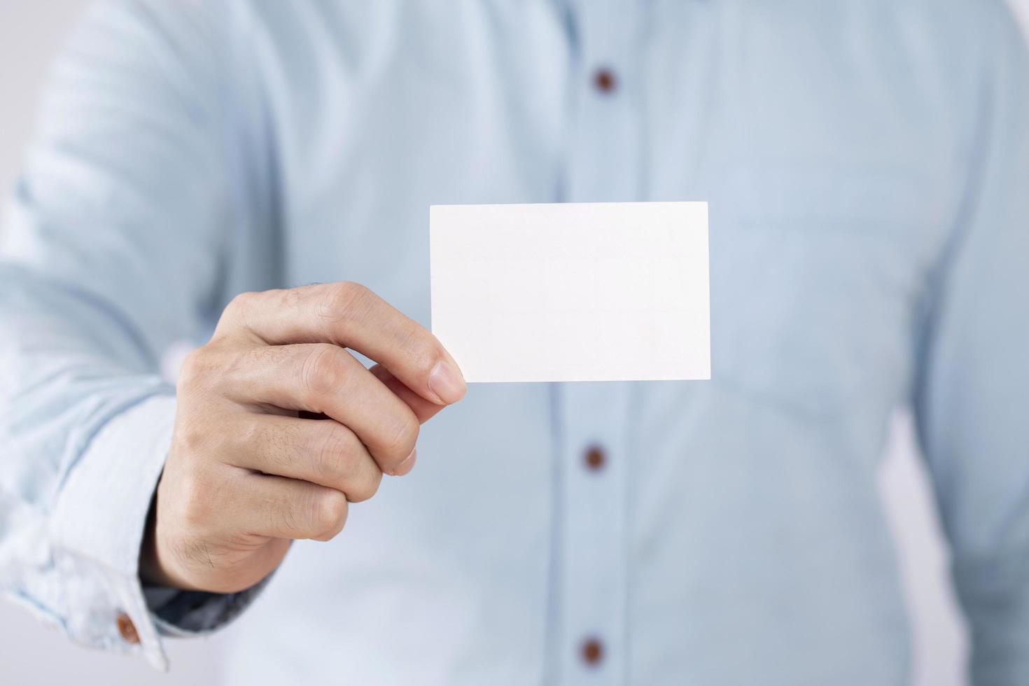 hombre de negocios que muestra una tarjeta de presentación en blanco sobre fondo blanco foto