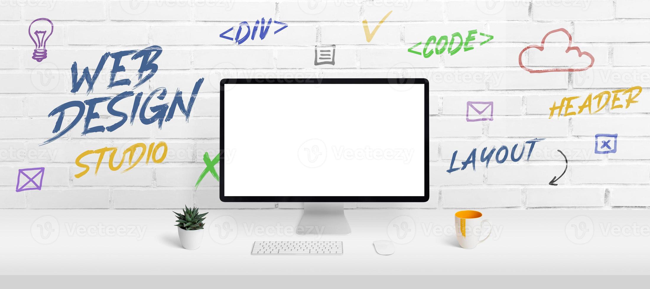 Web design studio concept with computer display mockup and work desk. Creative web page icons and inscriptions on the brick wall photo