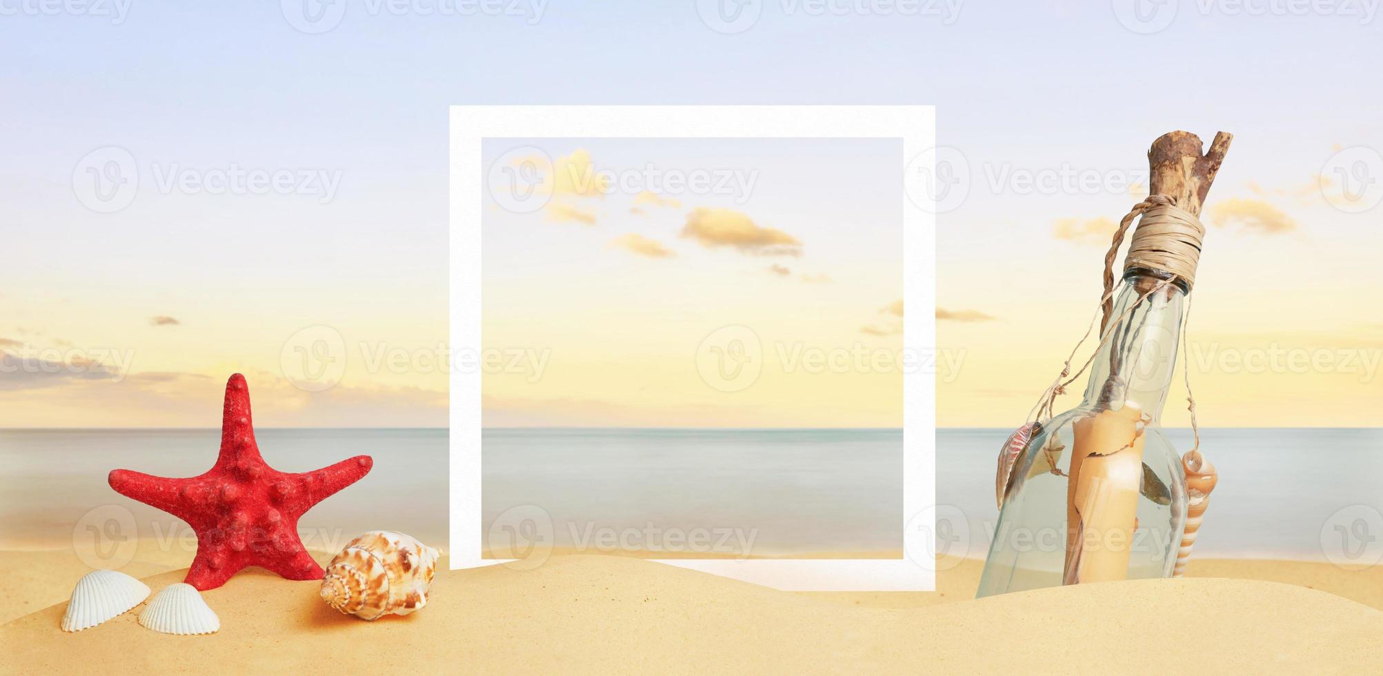 White square paper frame on beach sand surrounded by sea star, shells and message in the bottle. Copy space in the middle photo