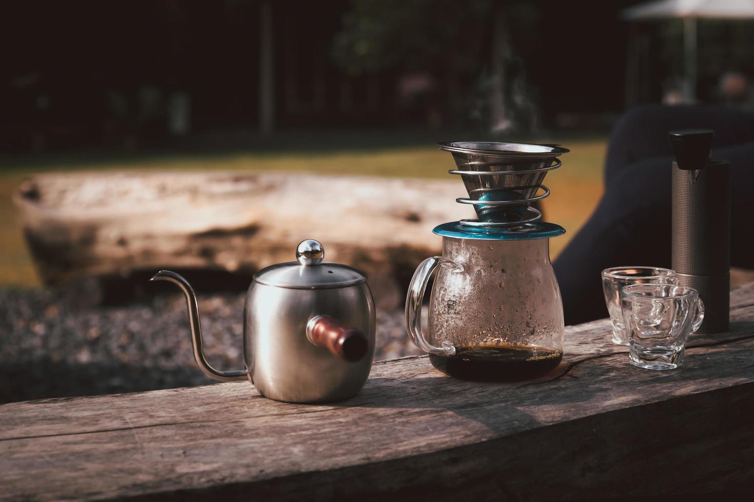 Coffee maker is placed on top of wooden chair in camping area. photo