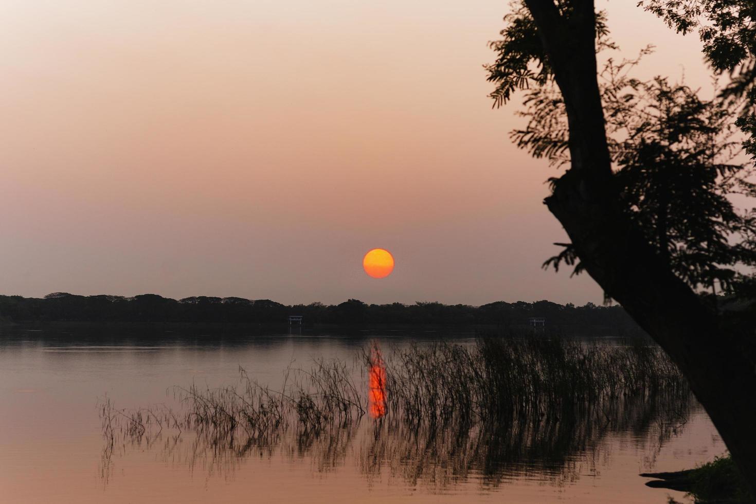 puesta de sol de silueta sobre el lago en un parque público. foto