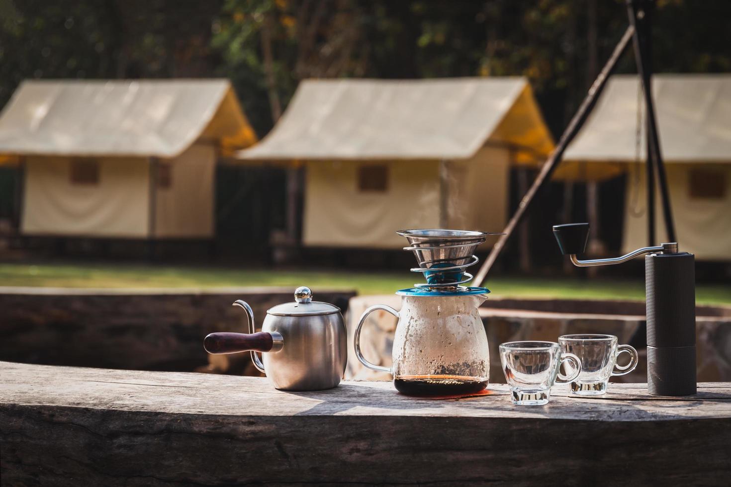 Coffee maker is placed on top of wooden chair in camping area. photo