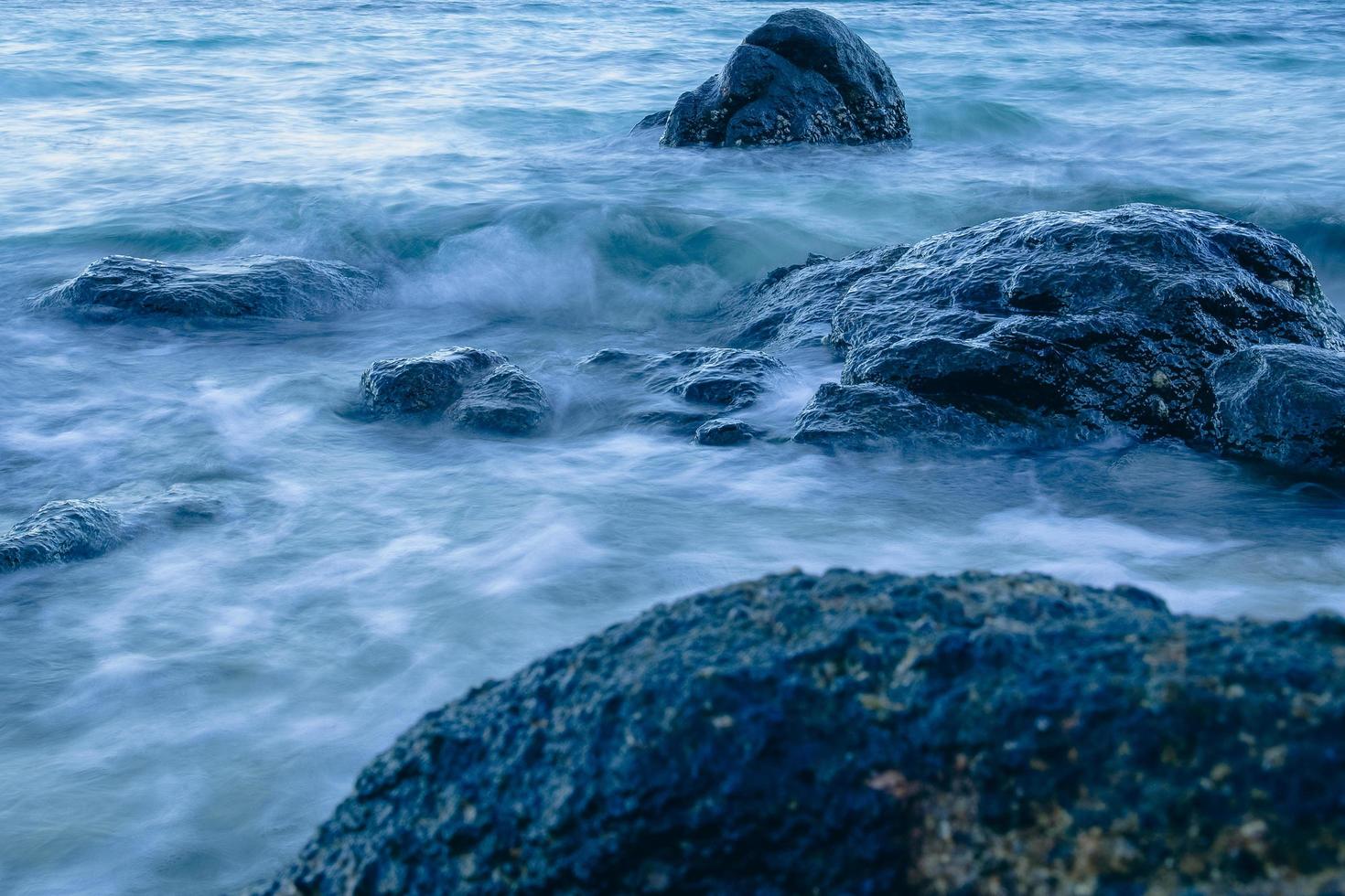Long exposure smooth ocean wave moving into rock. photo