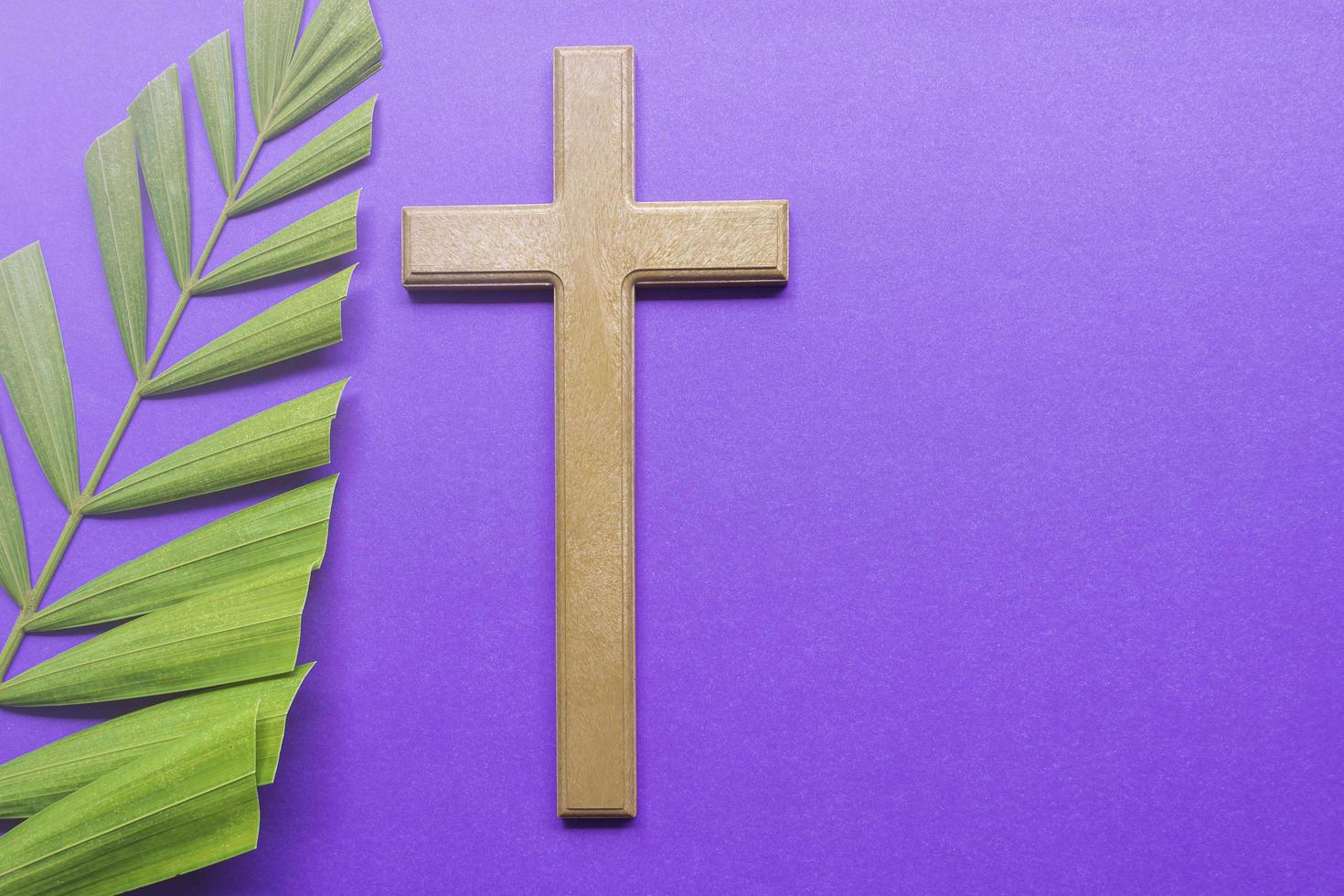 Cross and palm leaves on purple background. Lent season concept. photo