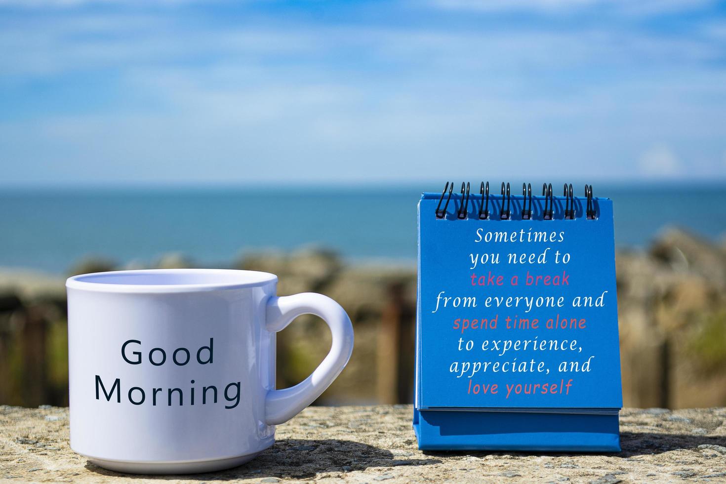 Motivational and Inspirational quote on blue standing notepad and coffee cup photo