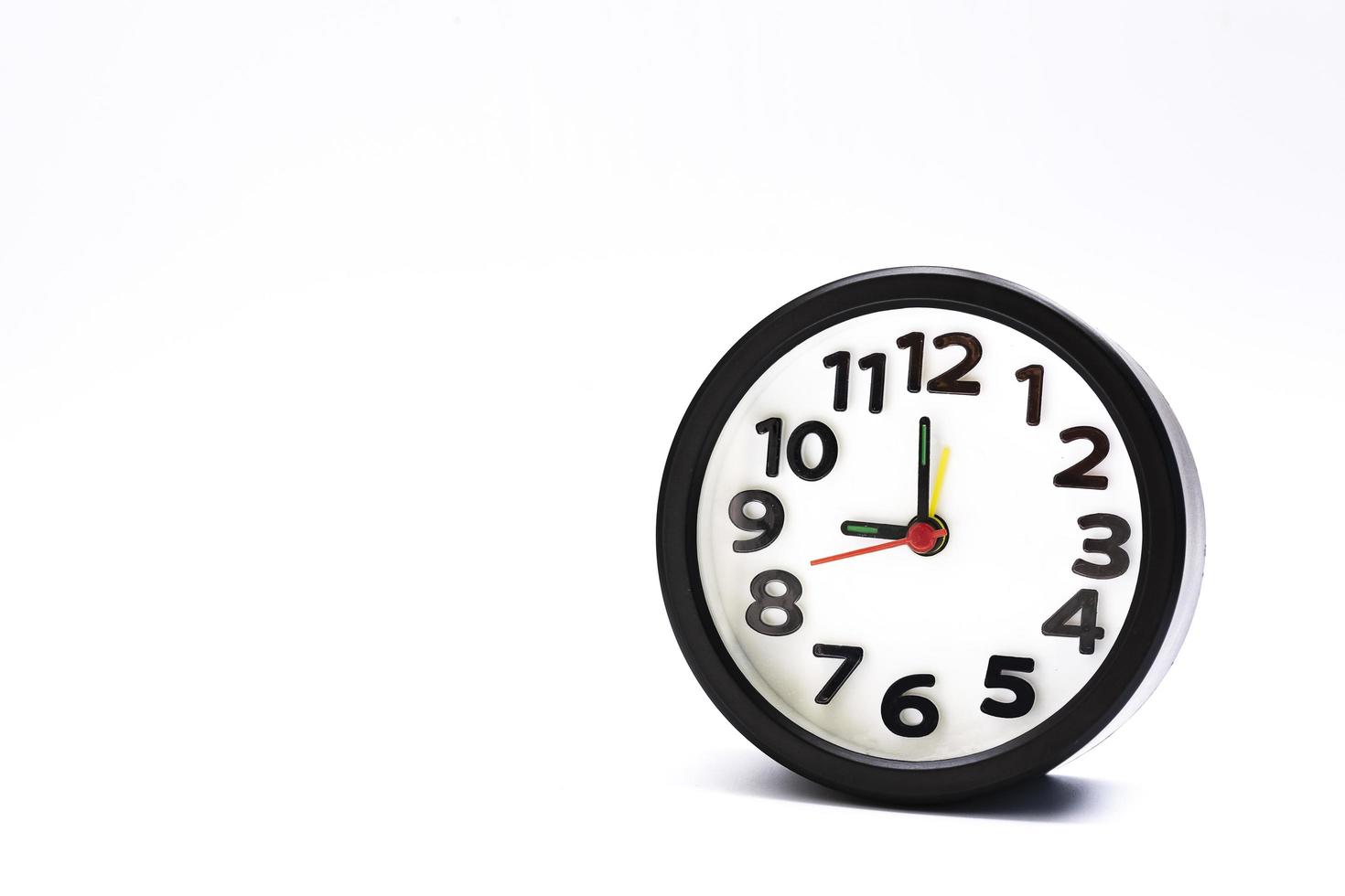 Black alarm clock isolated on white background. The clock set at 9 o'clock. photo