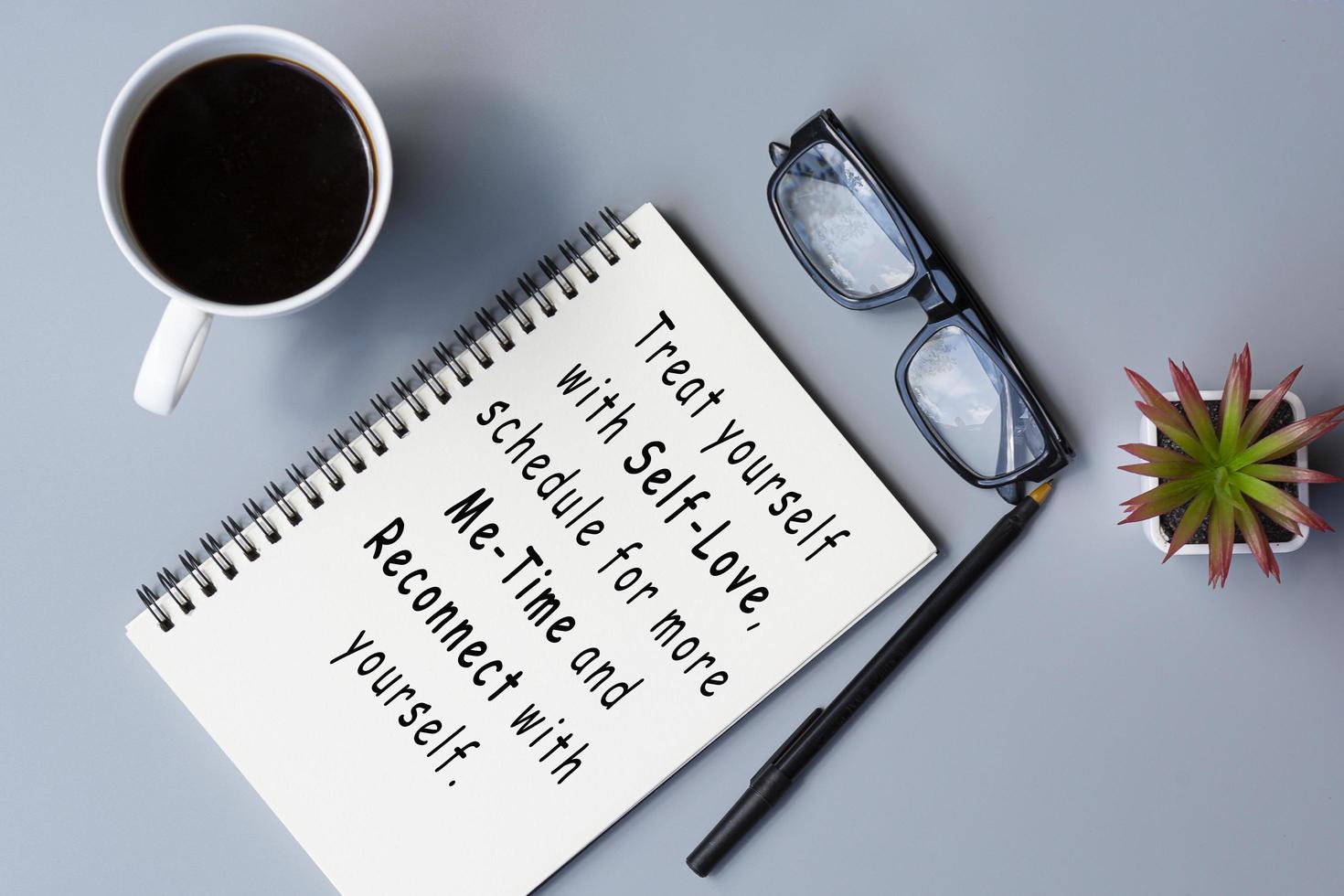 Motivational quote on notepad with coffee and reading glasses on a desk. photo