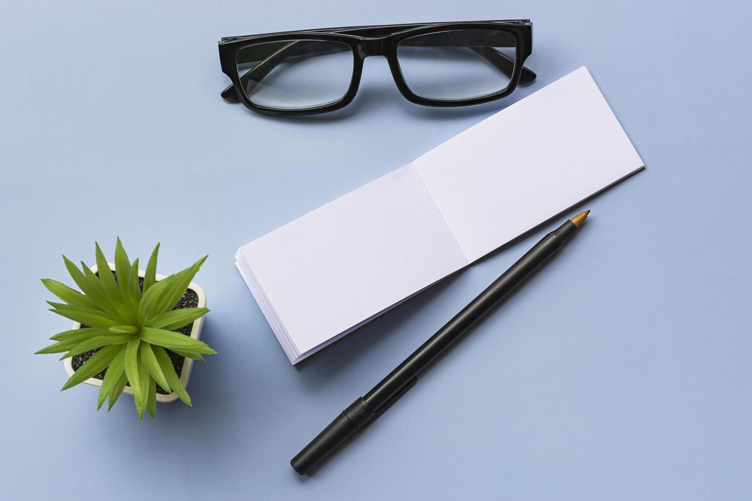 Notepad with reading glasses and potted plant. Message and reminder concept. photo