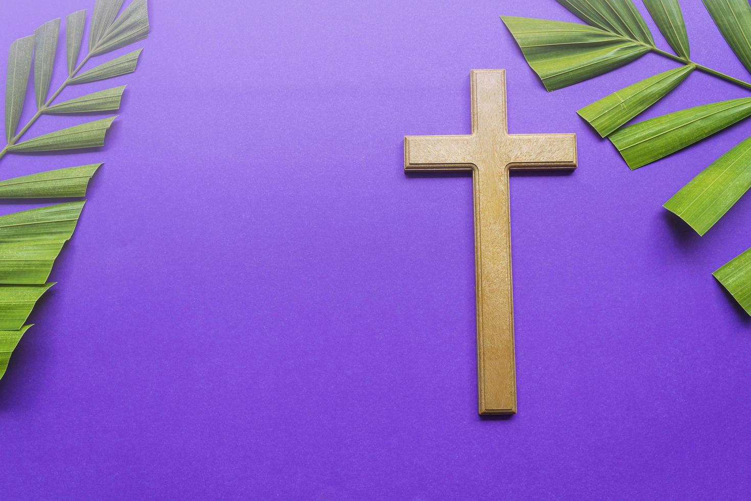 Cross and palm leaves on purple background. Lent season concept. photo