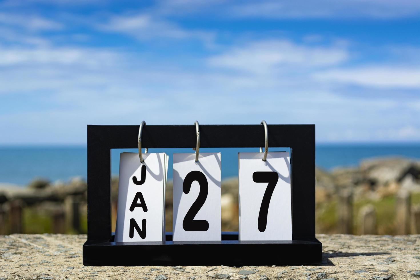 Jan 27 calendar date text on wooden frame with blurred background of ocean photo