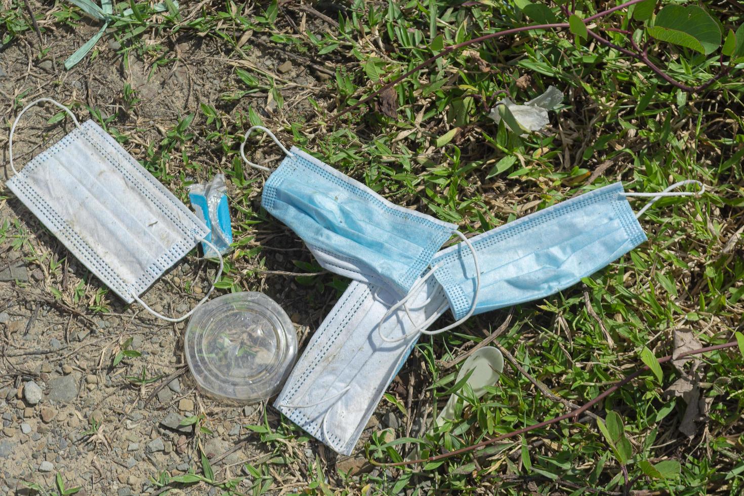 Trash and used surgical masks are thrown into grass. photo