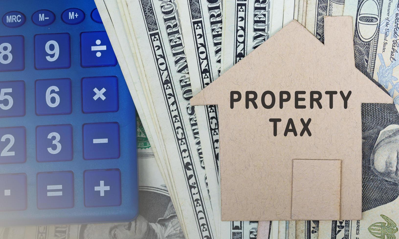 Tax text on brown paper house model with dollar banknotes on dark wooden table photo