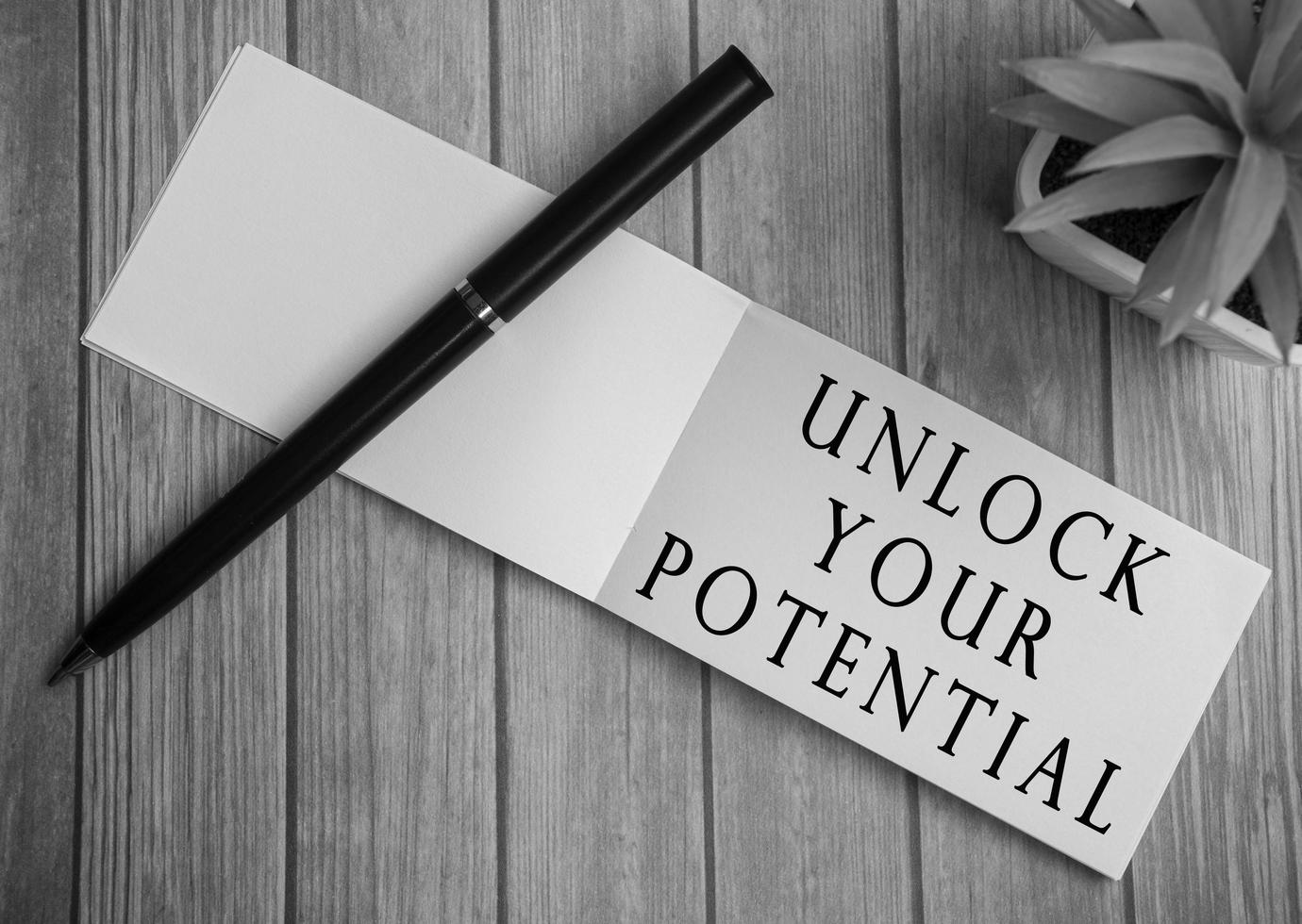 Unlock your potential text on notepad with potted plant on a wooden desk photo