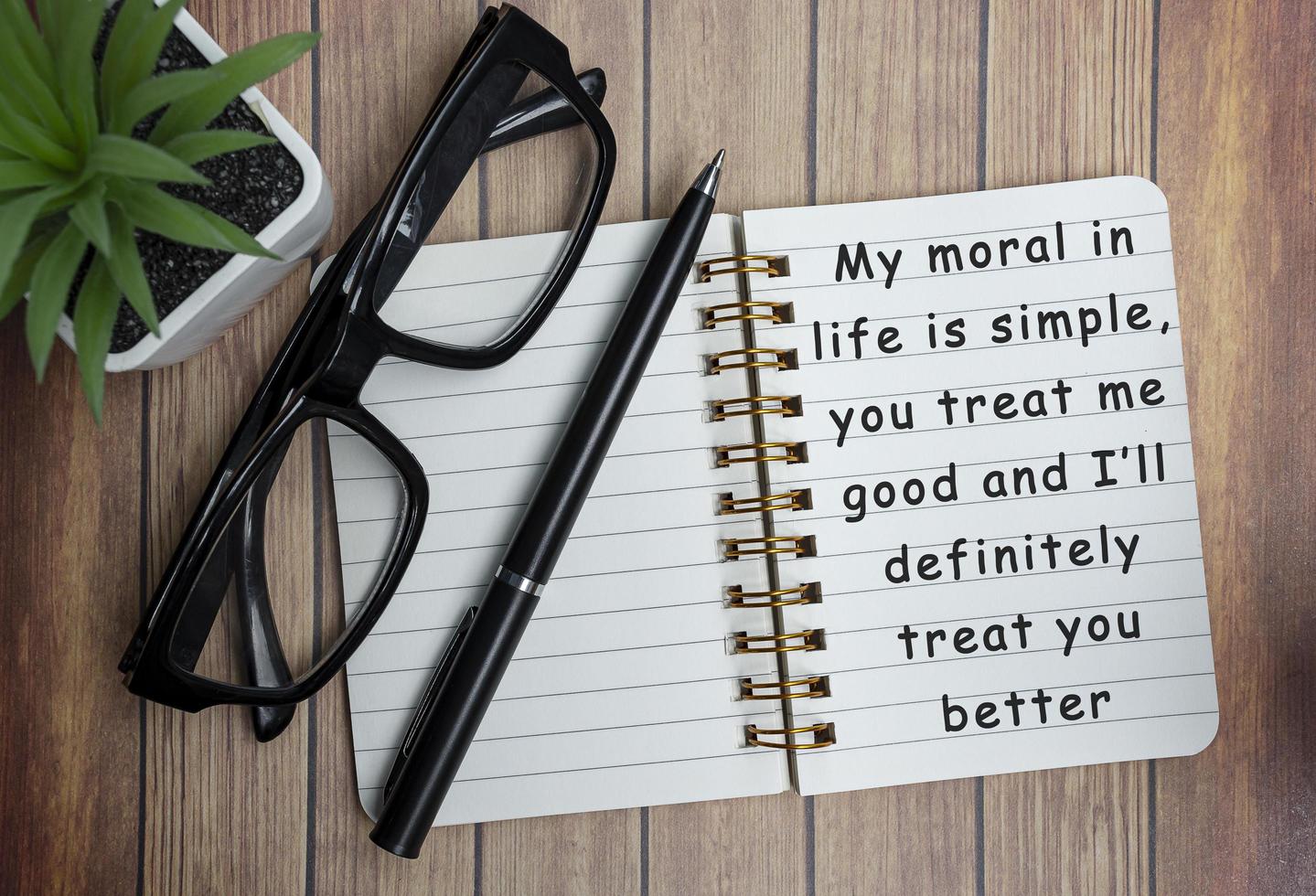 Motivational on a notepad with black reading glass on wooden desk photo