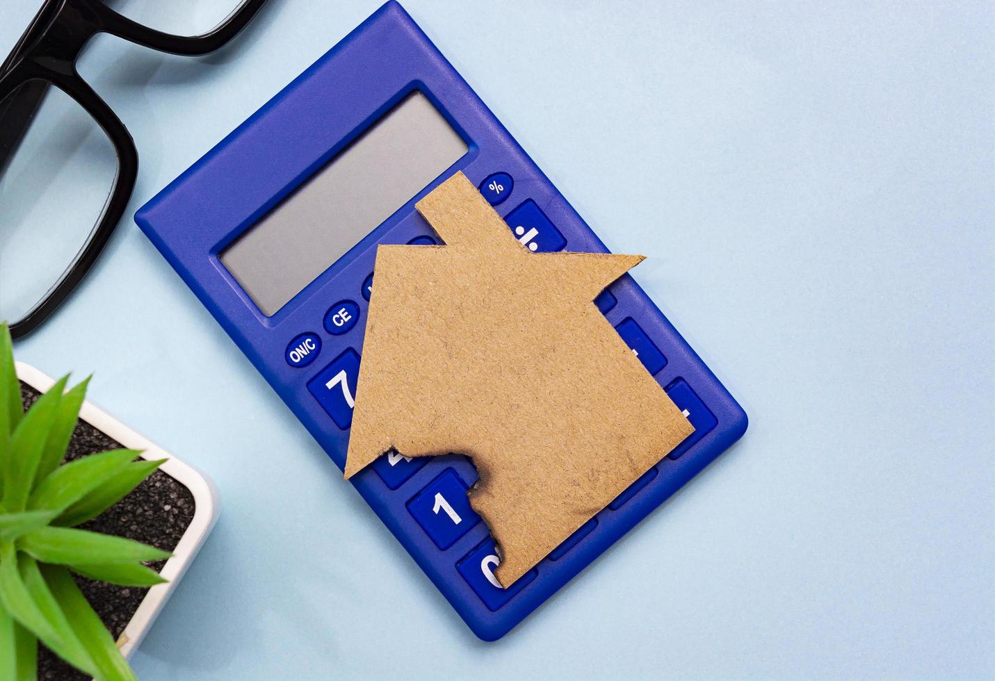Calculator with paper house model on top. Home insurance concept. photo