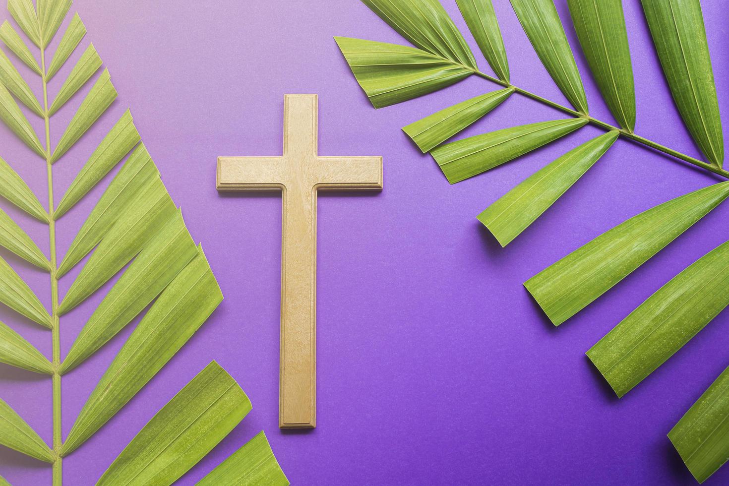 Cross and palm leaves on purple background. Lent season concept. photo