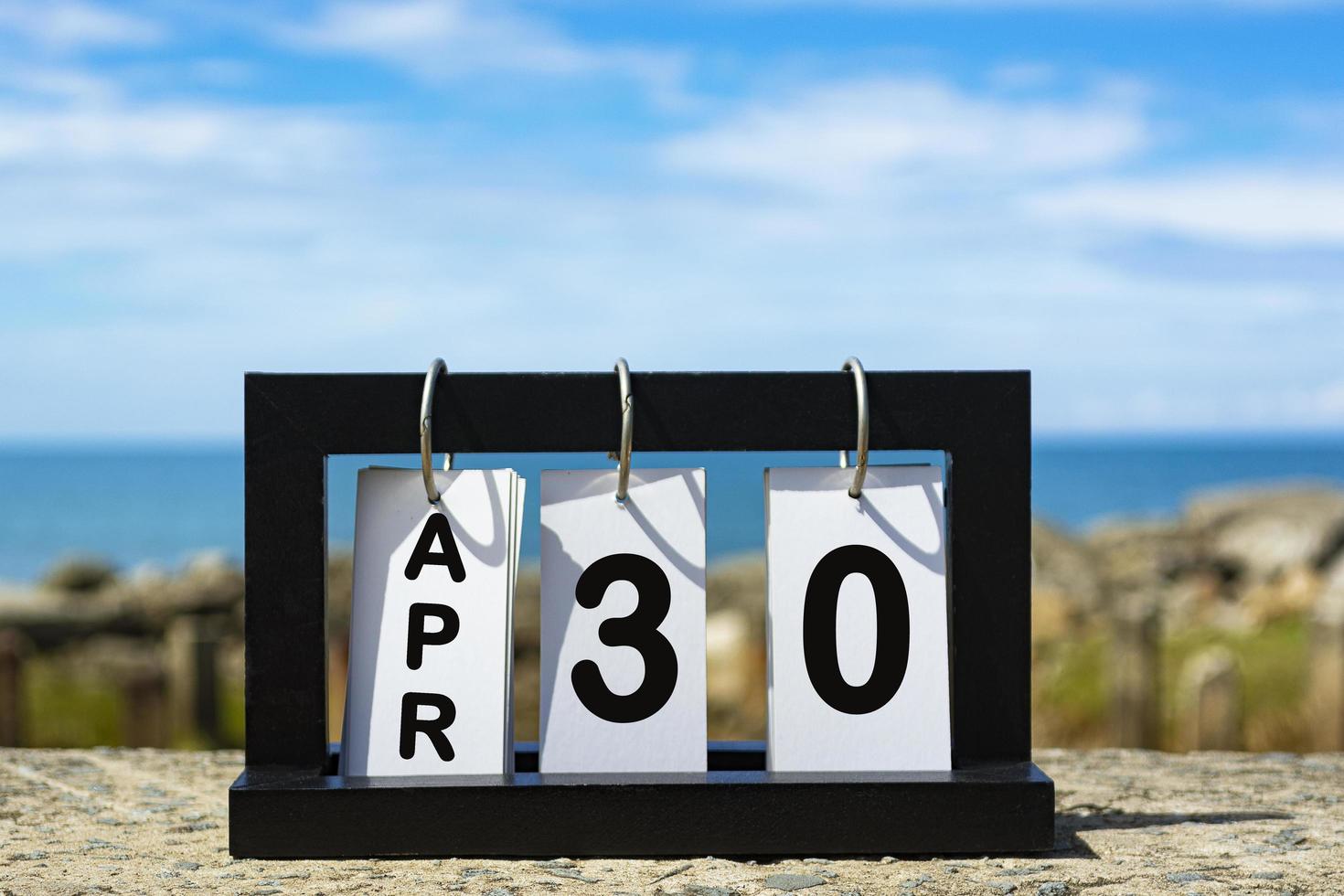 Apr 30 calendar date text on wooden frame with blurred background of ocean photo