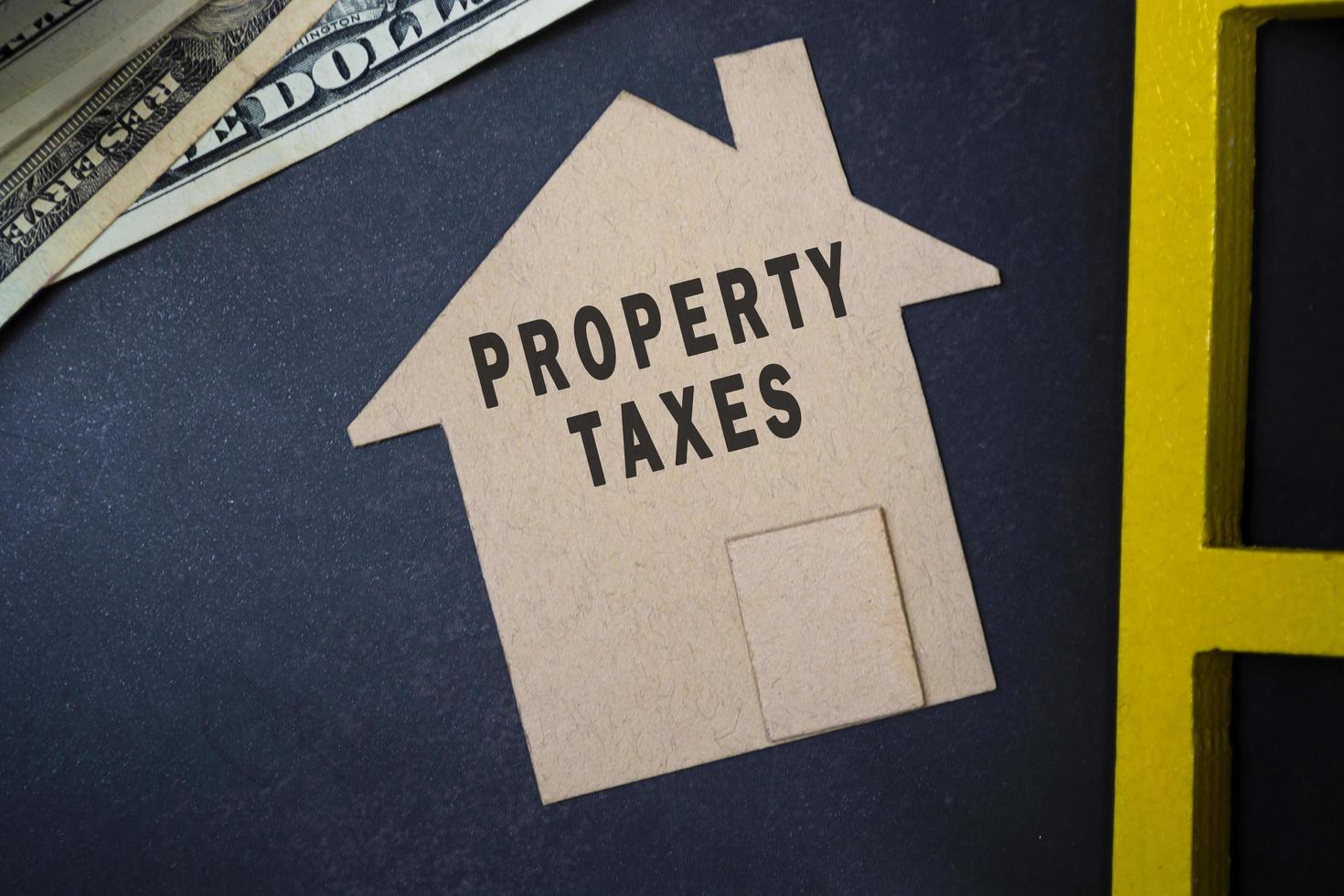 Property taxes text on brown paper house model with dollar banknotes on a desk photo