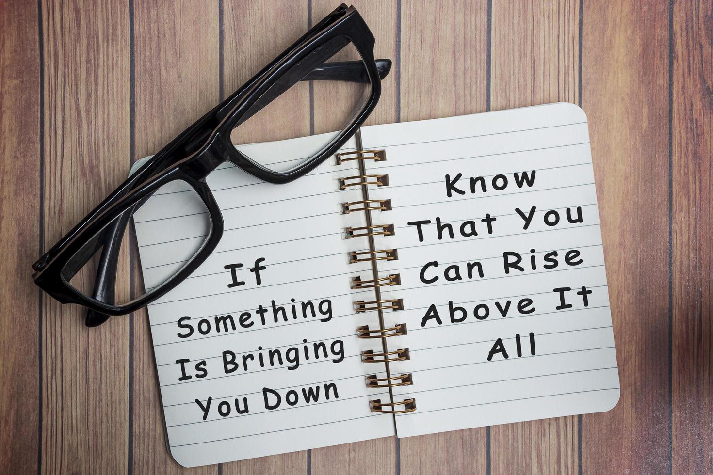 Motivational on a notepad with black reading glass on wooden desk photo