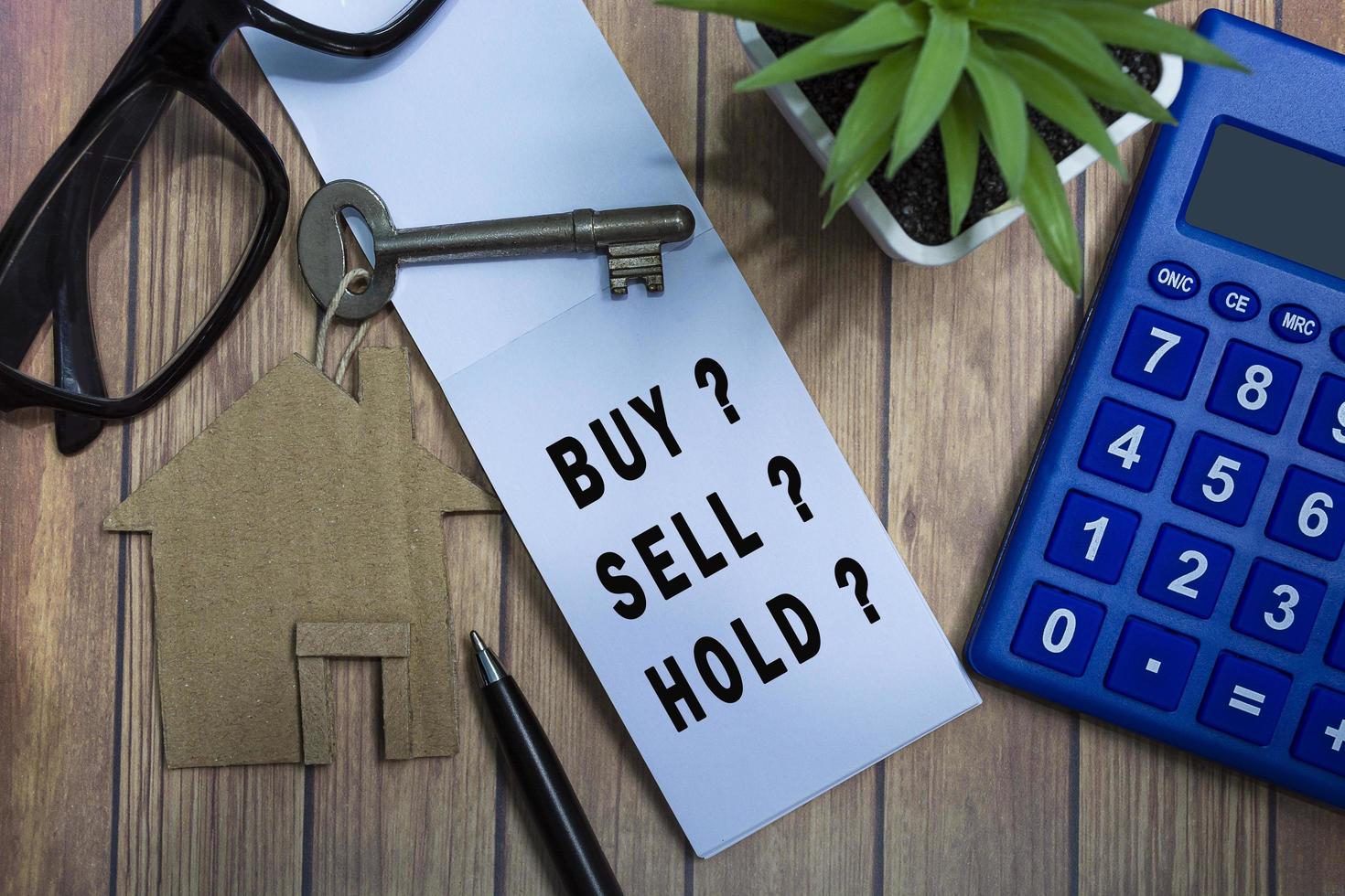 Text on notepad with house model and key on wooden desk. Investment concept. photo