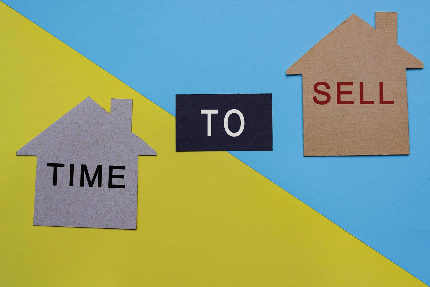 Time to sell text on paper house model with colored paper background photo