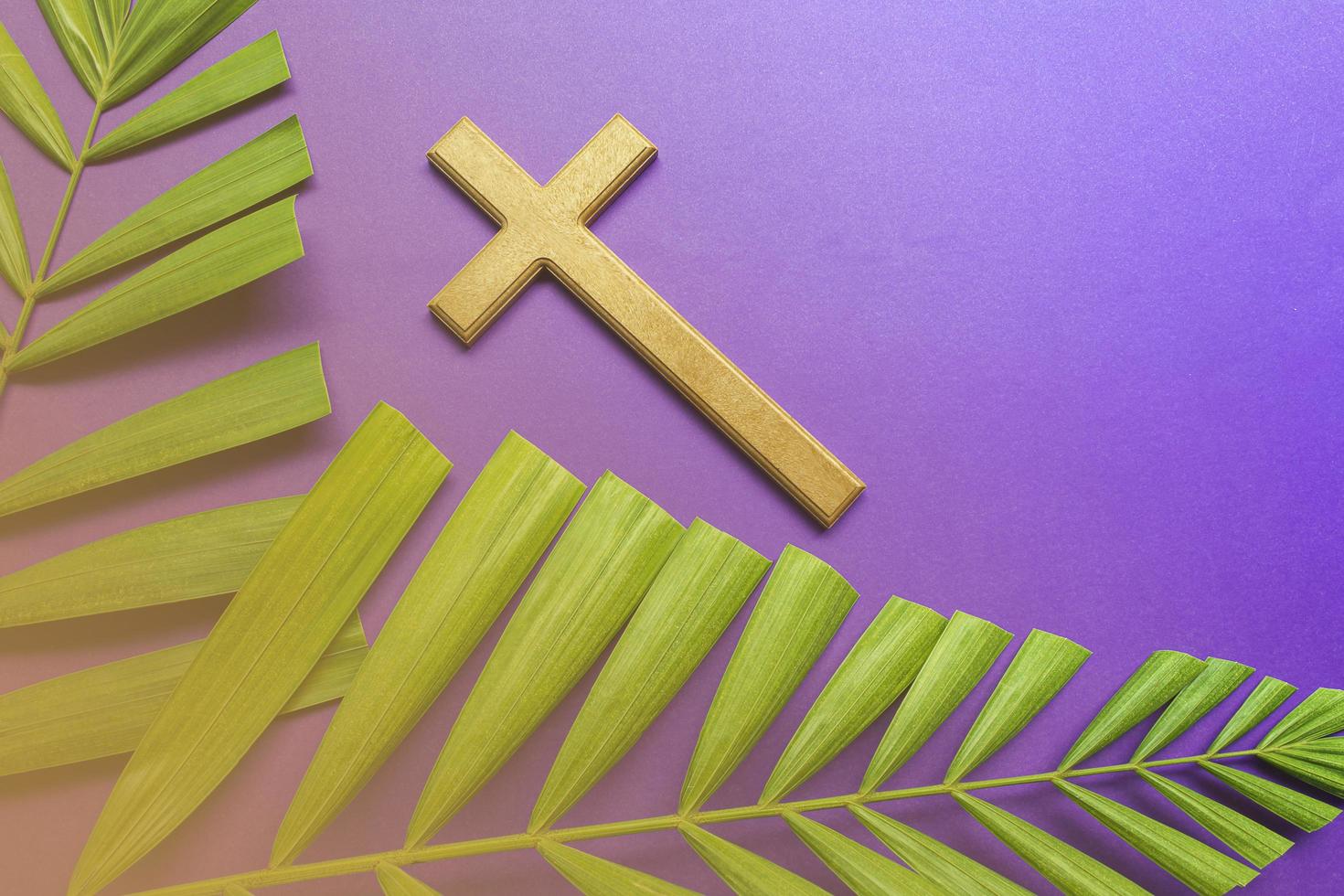 Cross and palm leaves on purple background. Lent season concept. photo