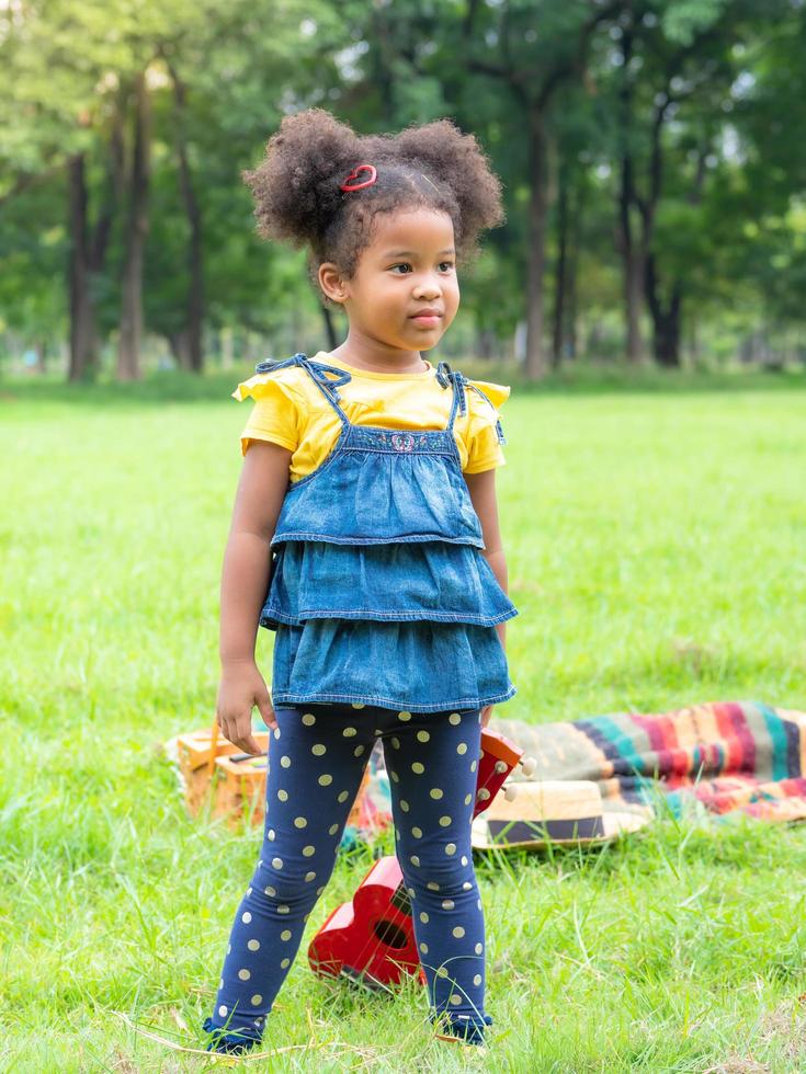 The girl stands on the grass, wears headphones and is learning to play ukulele strings photo