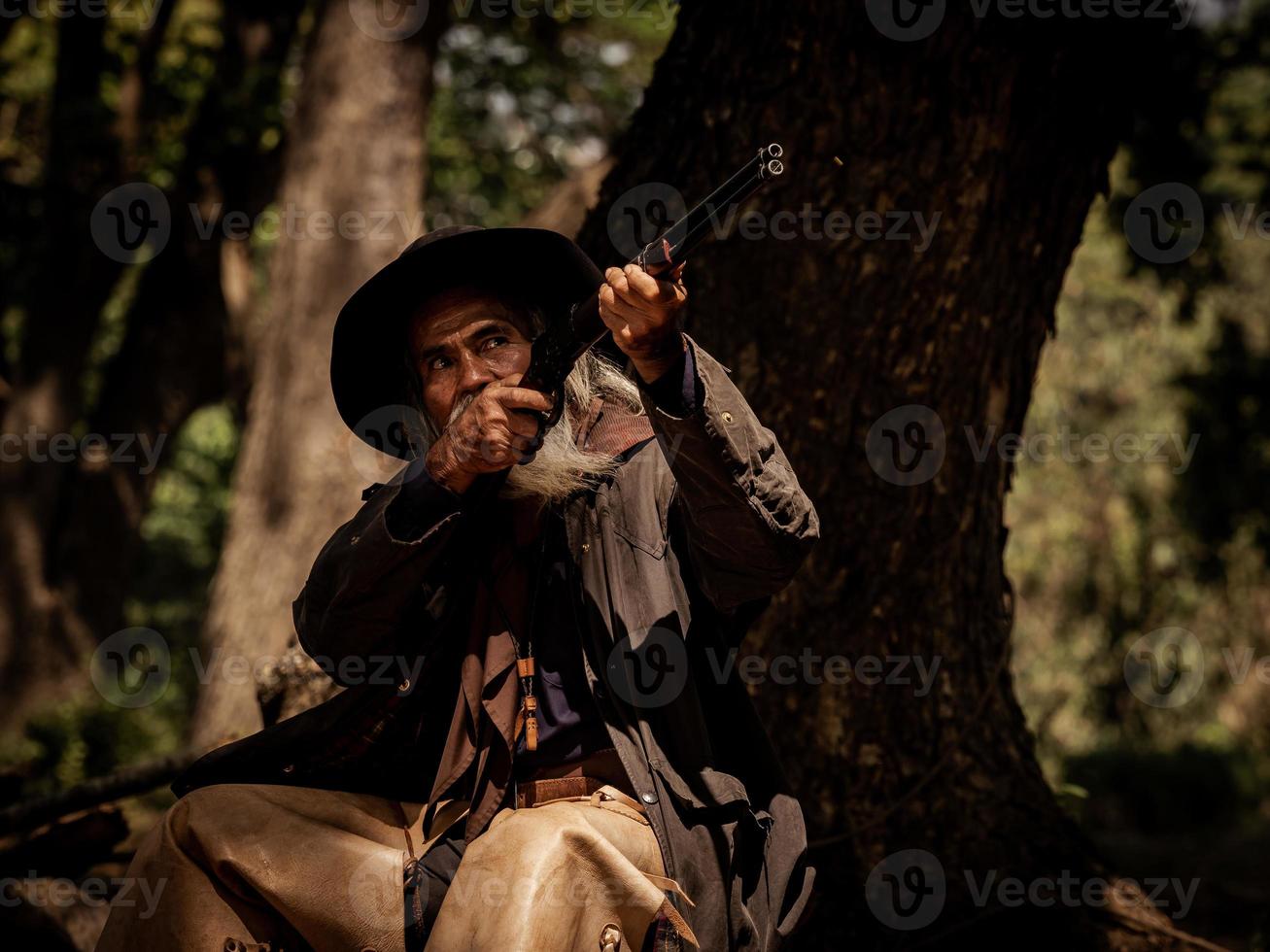 The senior cowboy is aiming the rifle at the attacker, While security surveillance in rural farm areas photo