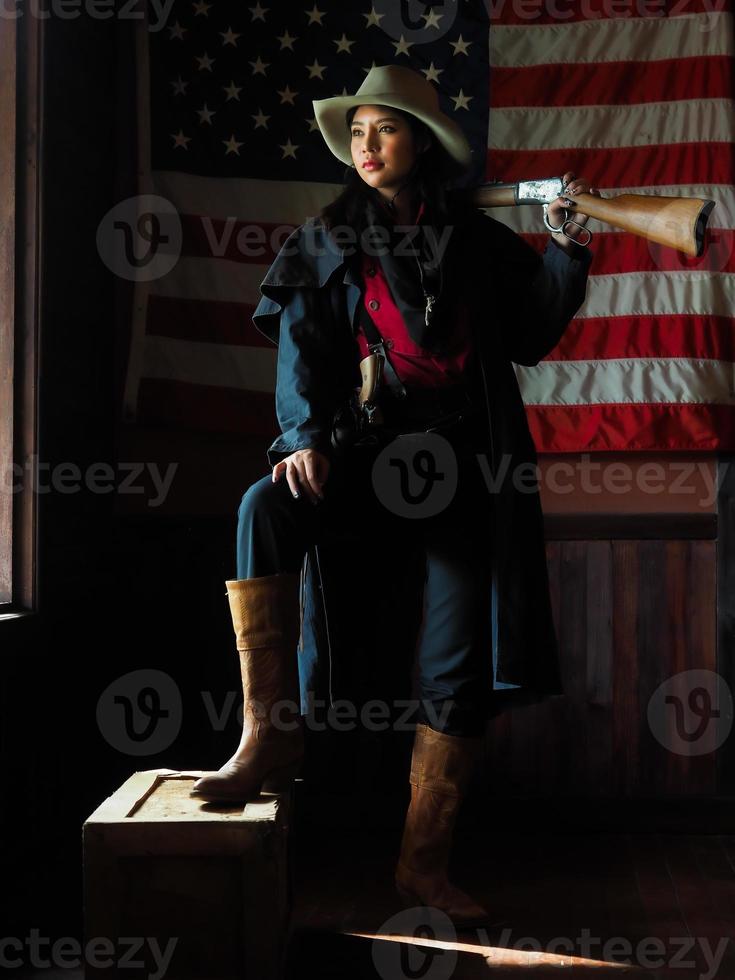 A Western cowgirl is preparing to use a gun to defend herself in a land where people must protect themselves photo