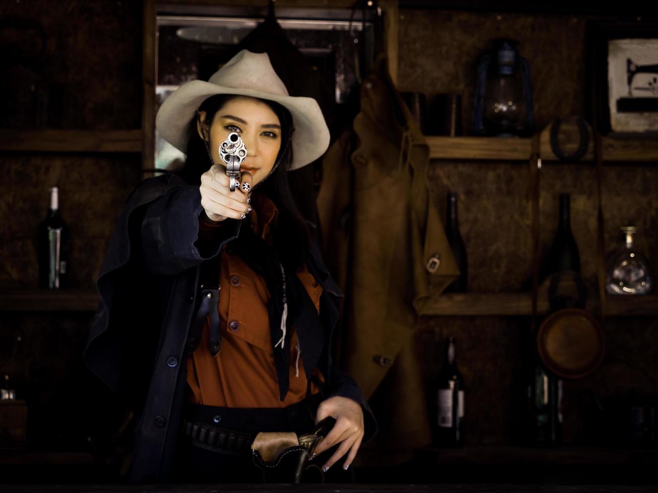 A Western cowgirl is preparing to use a gun to defend herself in a land where people must protect themselves photo