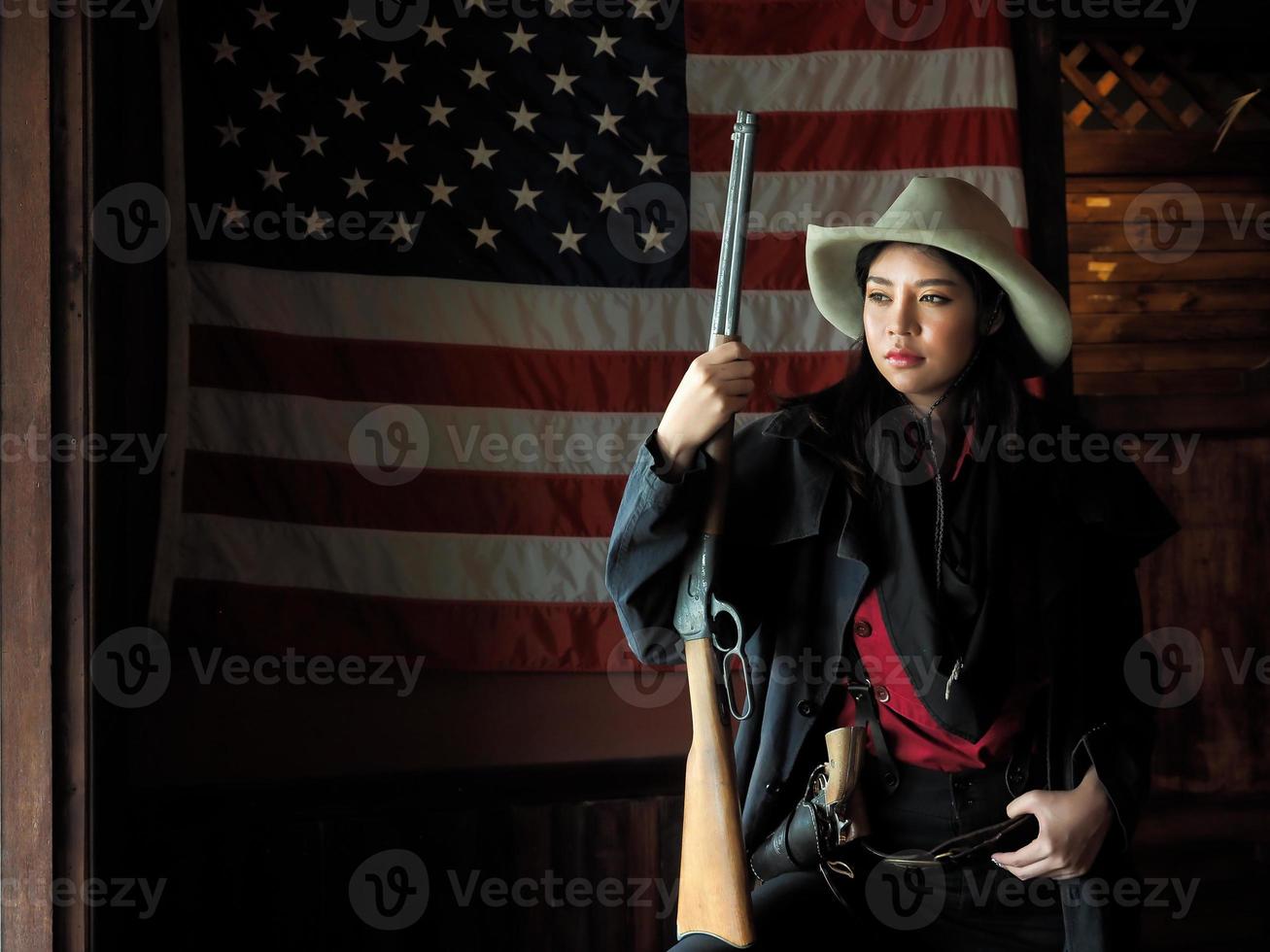 A Western cowgirl is preparing to use a gun to defend herself in a land where people must protect themselves photo