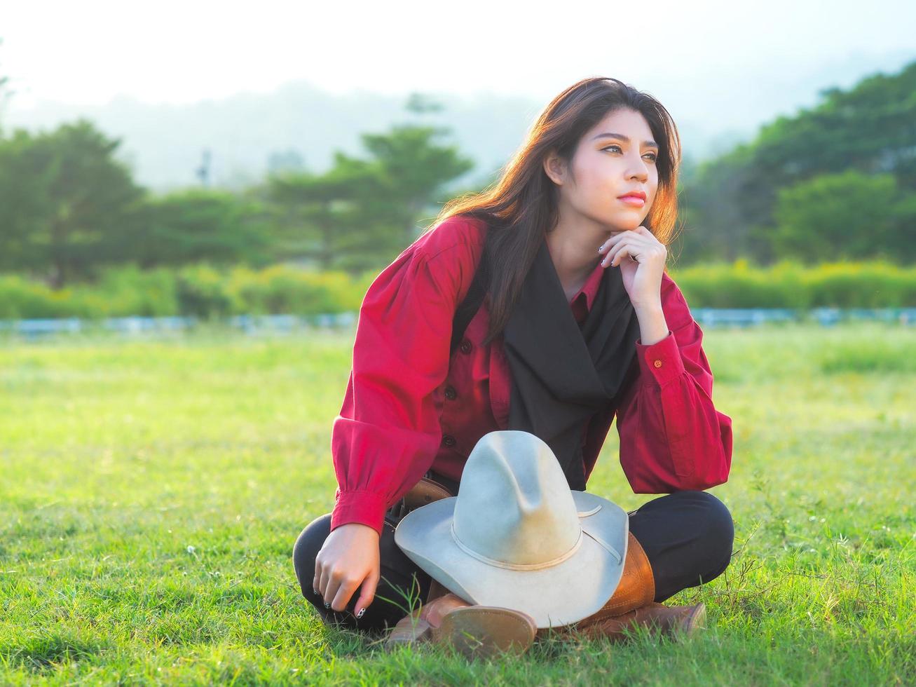 A beautiful western cowgirl sitting on a meadow on a farm after hard work photo