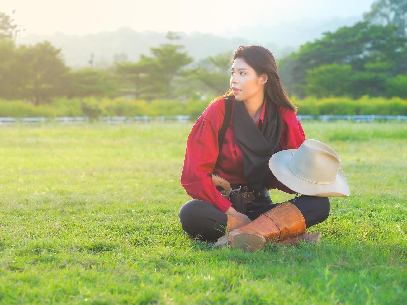 A beautiful western cowgirl sitting on a meadow on a farm after hard work photo