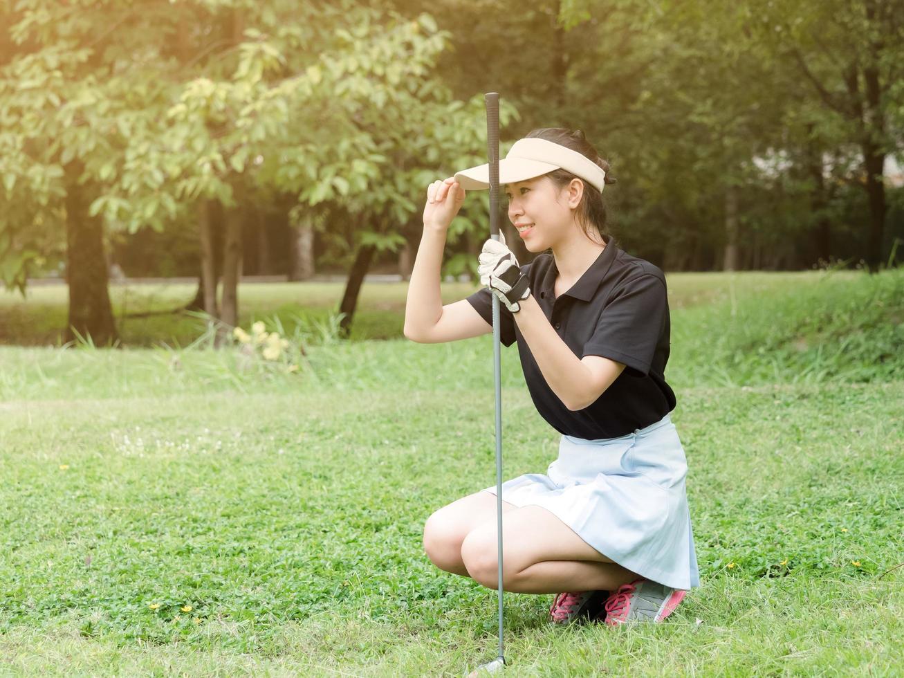 A young Asian golfer looks at the line on the golf course and prepares to put the ball during the match photo