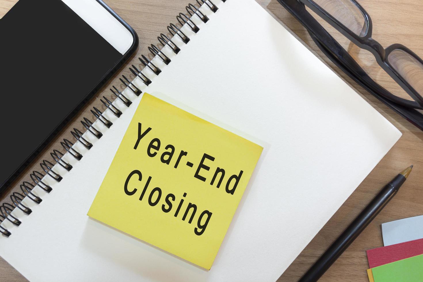 Text on yellow note with notepad on wooden desk - Year-end closing photo