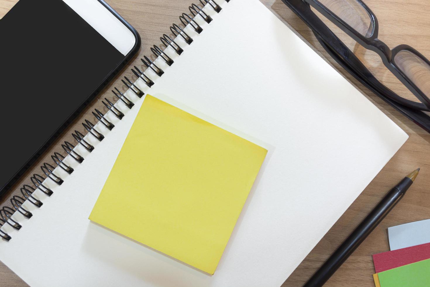 Notepad with yellow note on wooden desk. Flat lay. Directly above photo