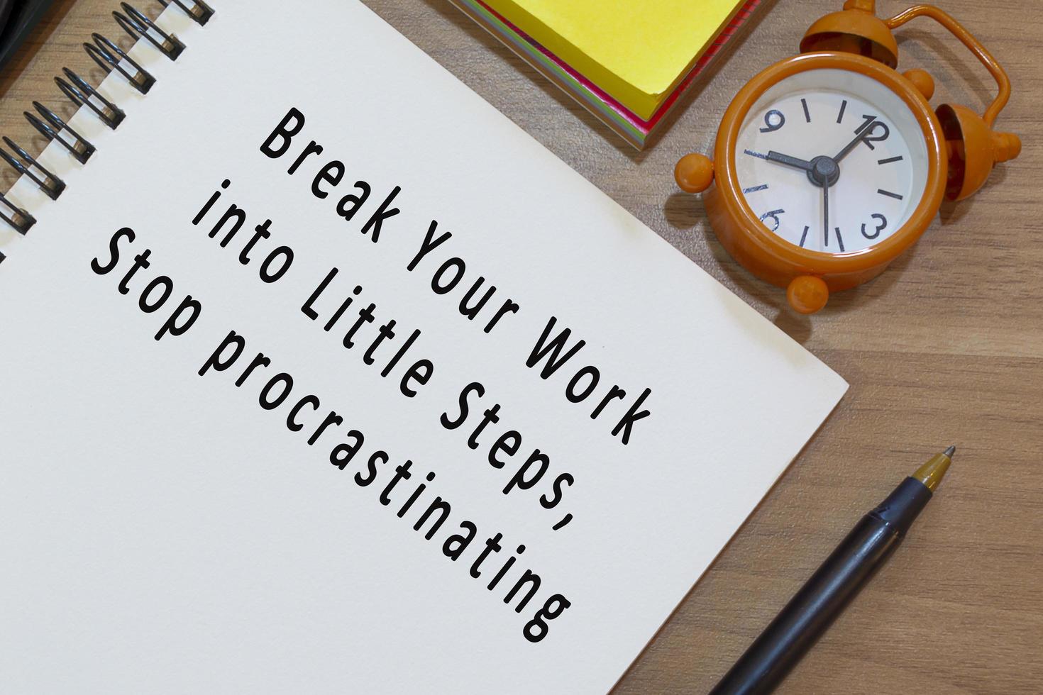 Text on notepad with alarm clock on wooden desk. Work concept photo