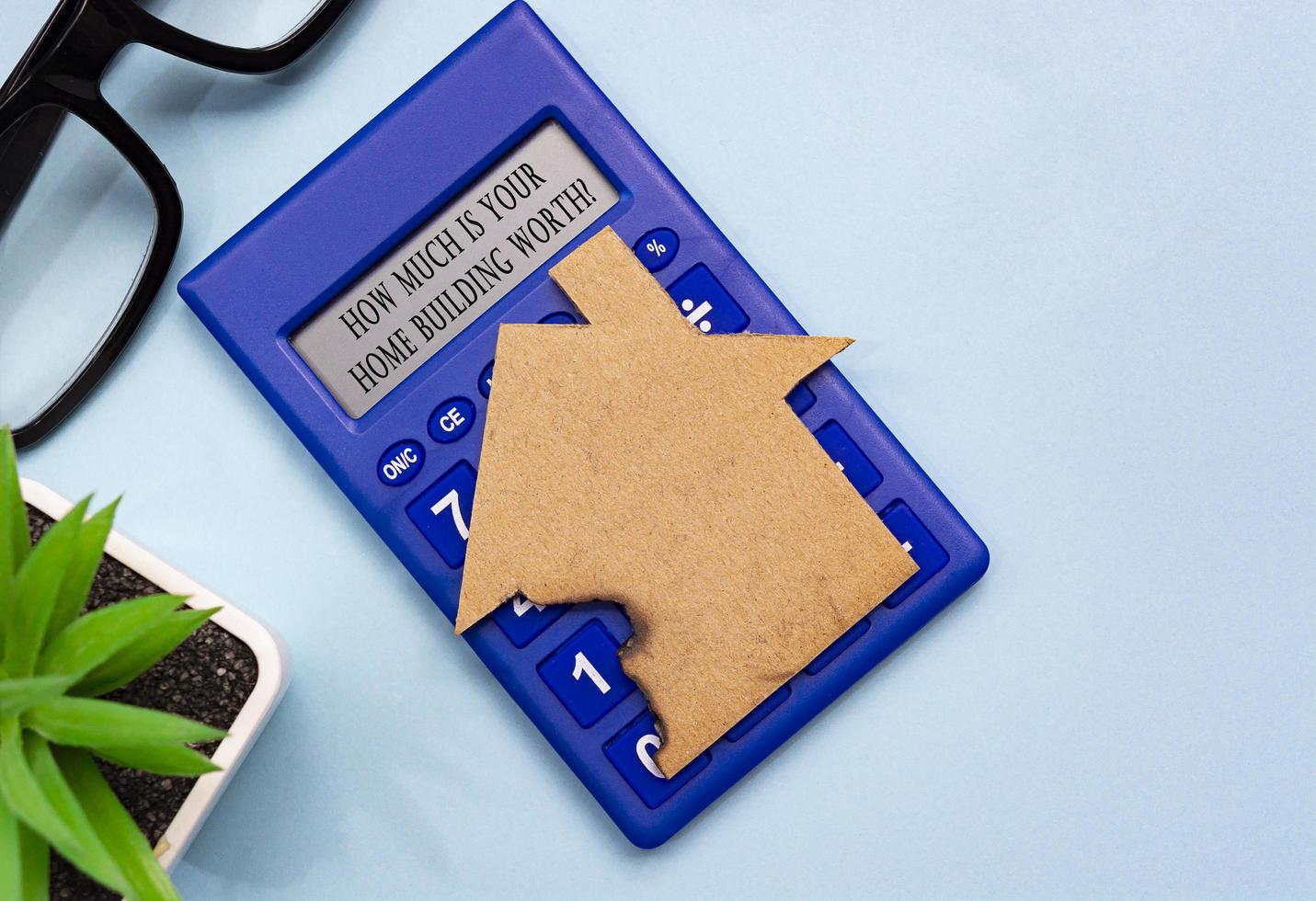 Text on burned paper house model on blue background. Home insurance concept. photo