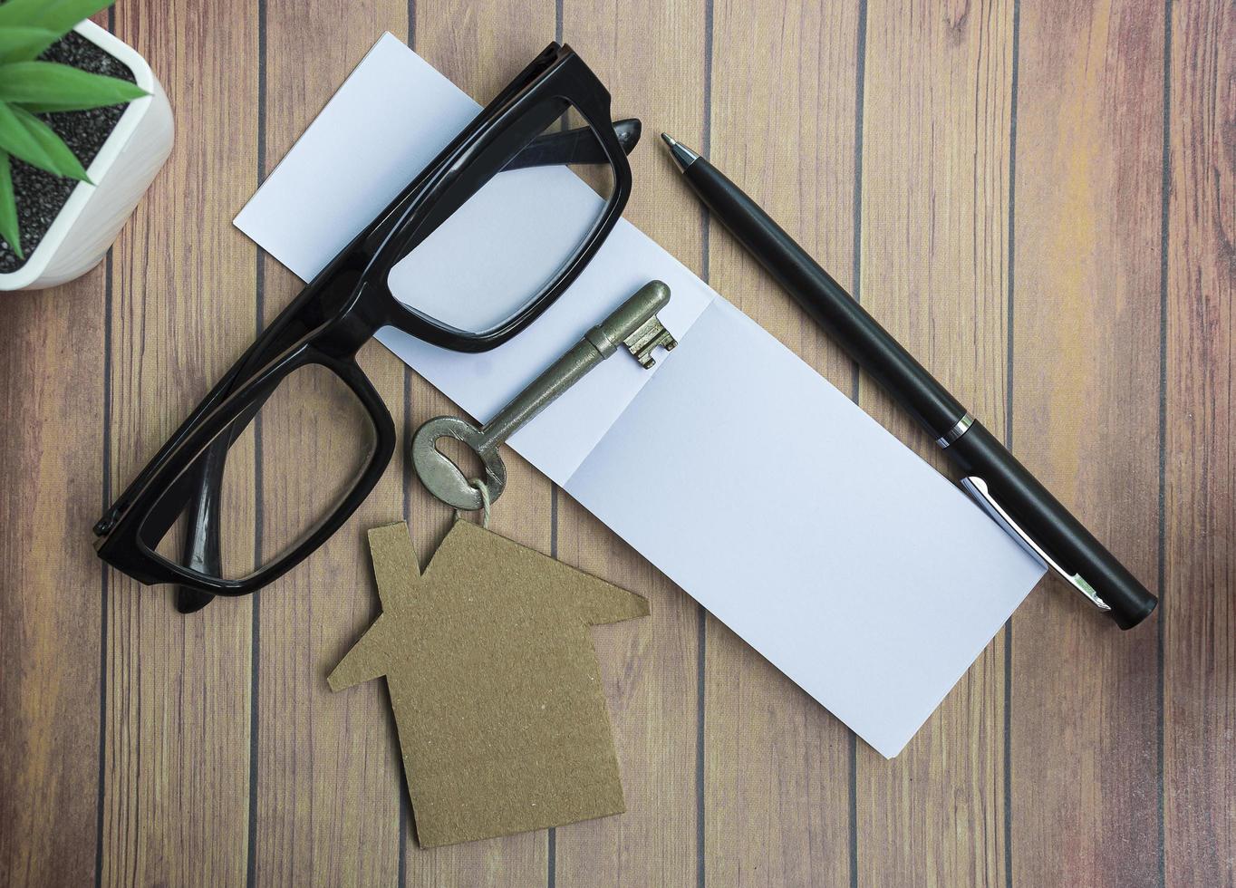 Notepad with house model and key on wooden desk. Directly above. Flat lay. photo