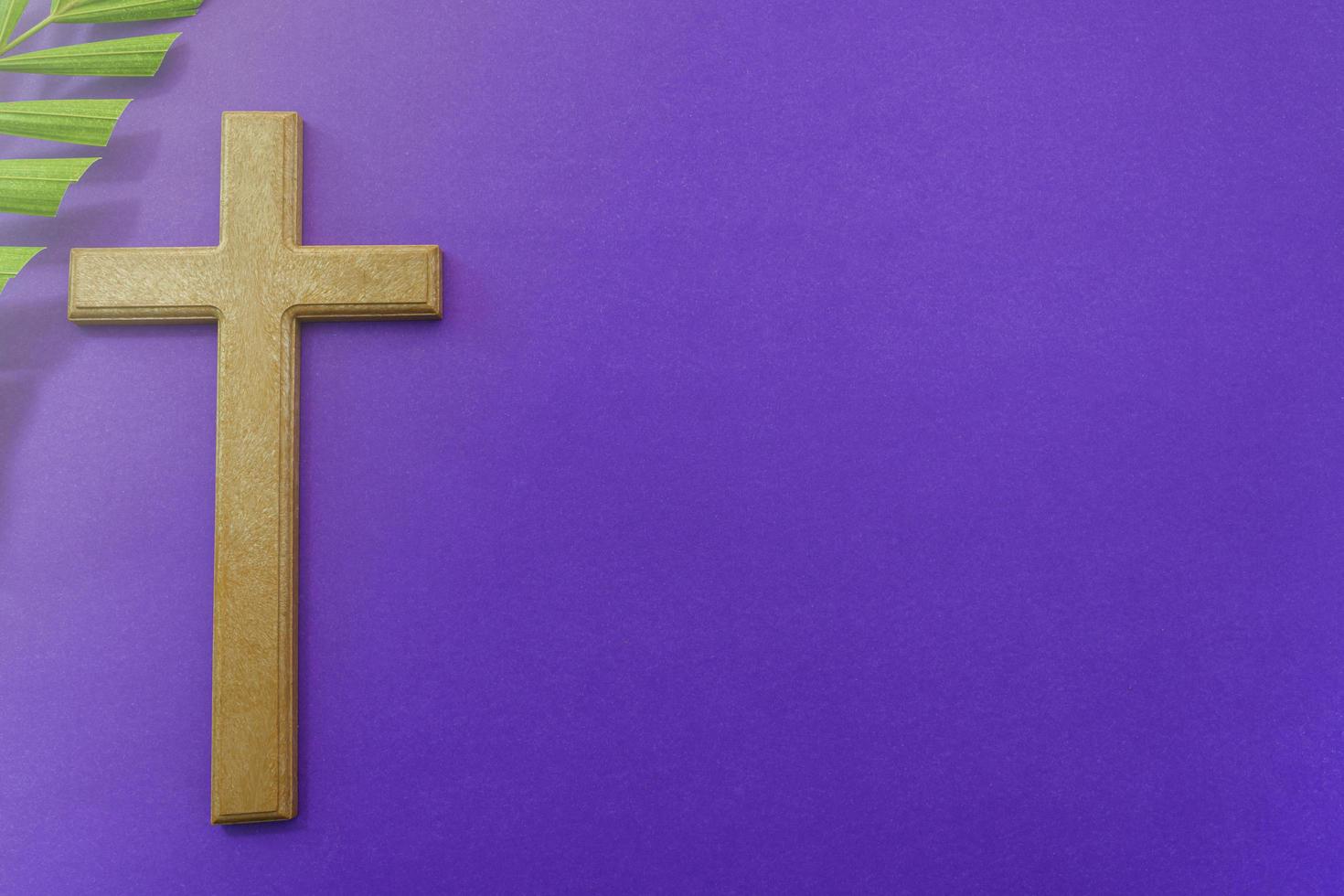 Cross and palm leaves on purple background. Lent season concept. photo